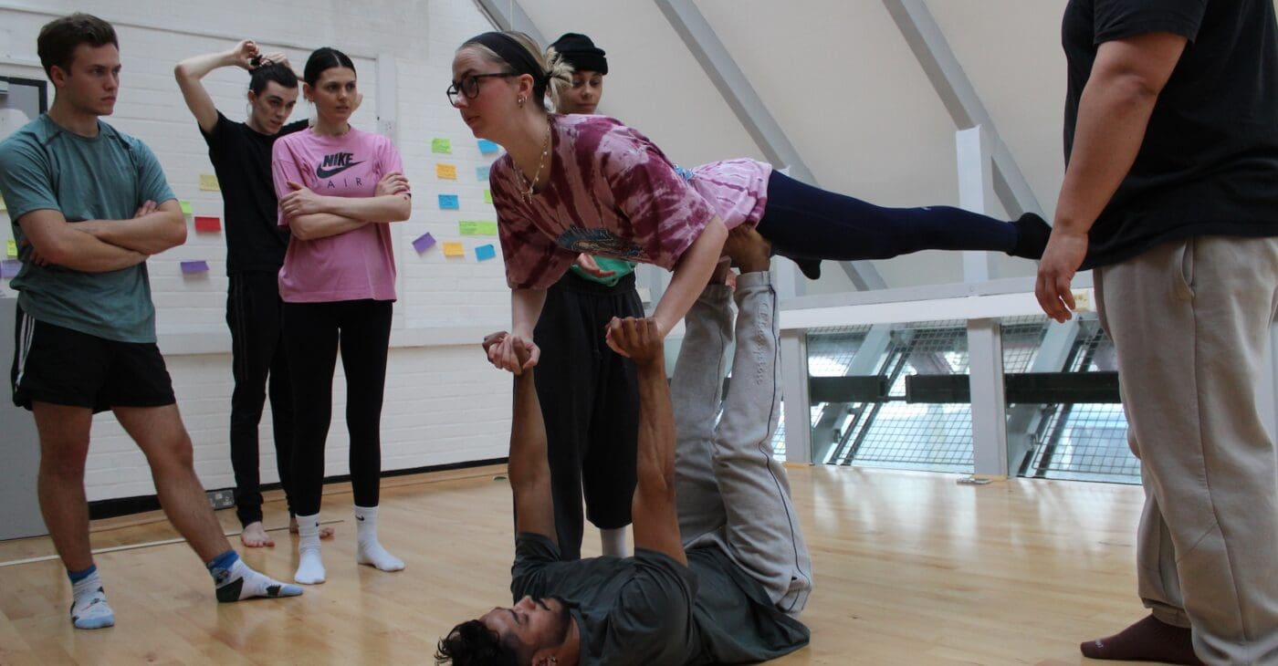 A group of acrobats practice in a studio
